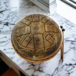 Image of a 10 inch Tongue drum with 7 chakra embossings placed on marble top