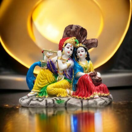 Radha Krishna Idol sitting besides each other in front of a tree listening to the blissful tones of Krishna flute