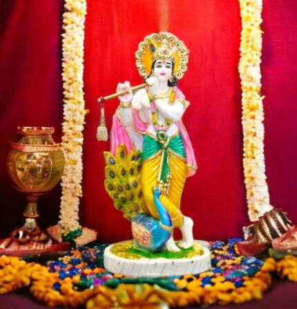 A beautiful Idol of Krishna playing his flute standing along a peacock.