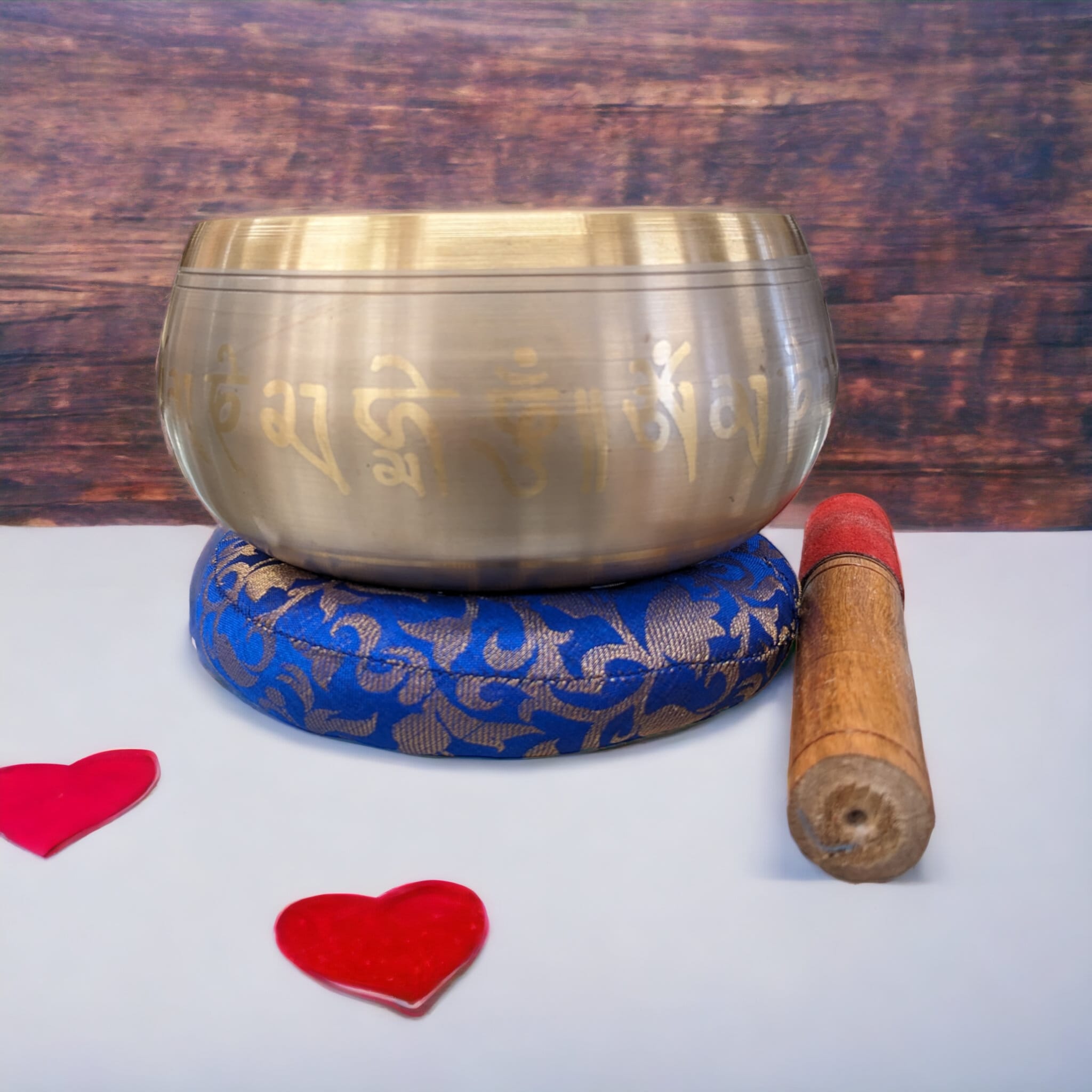 Image of a large tibetan singing bowl placed on a cushion with a wooden mallet besides it