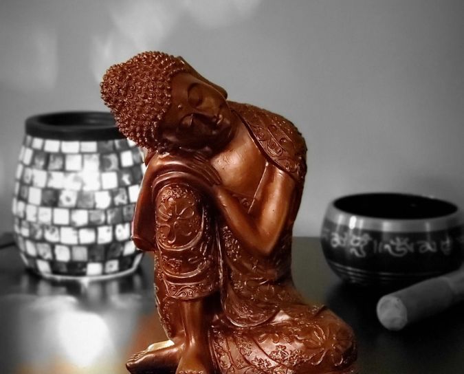 Image of a Meditating Buddha Idol in front of a singing bowl and incense burner and aroma oil diffuser