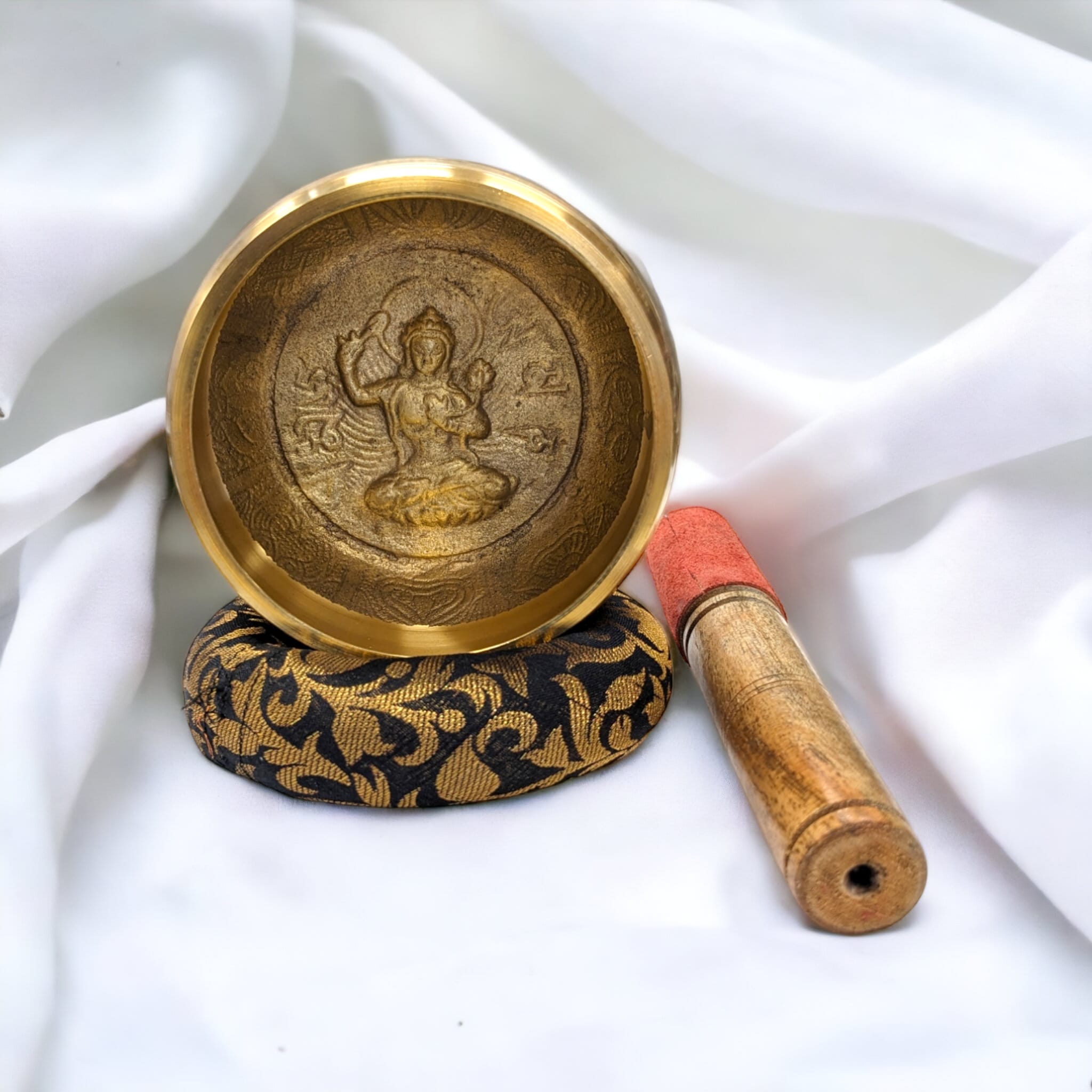 Image of a Tibetan Singing bowl with a wooden mallet placed on a Cushion Cover