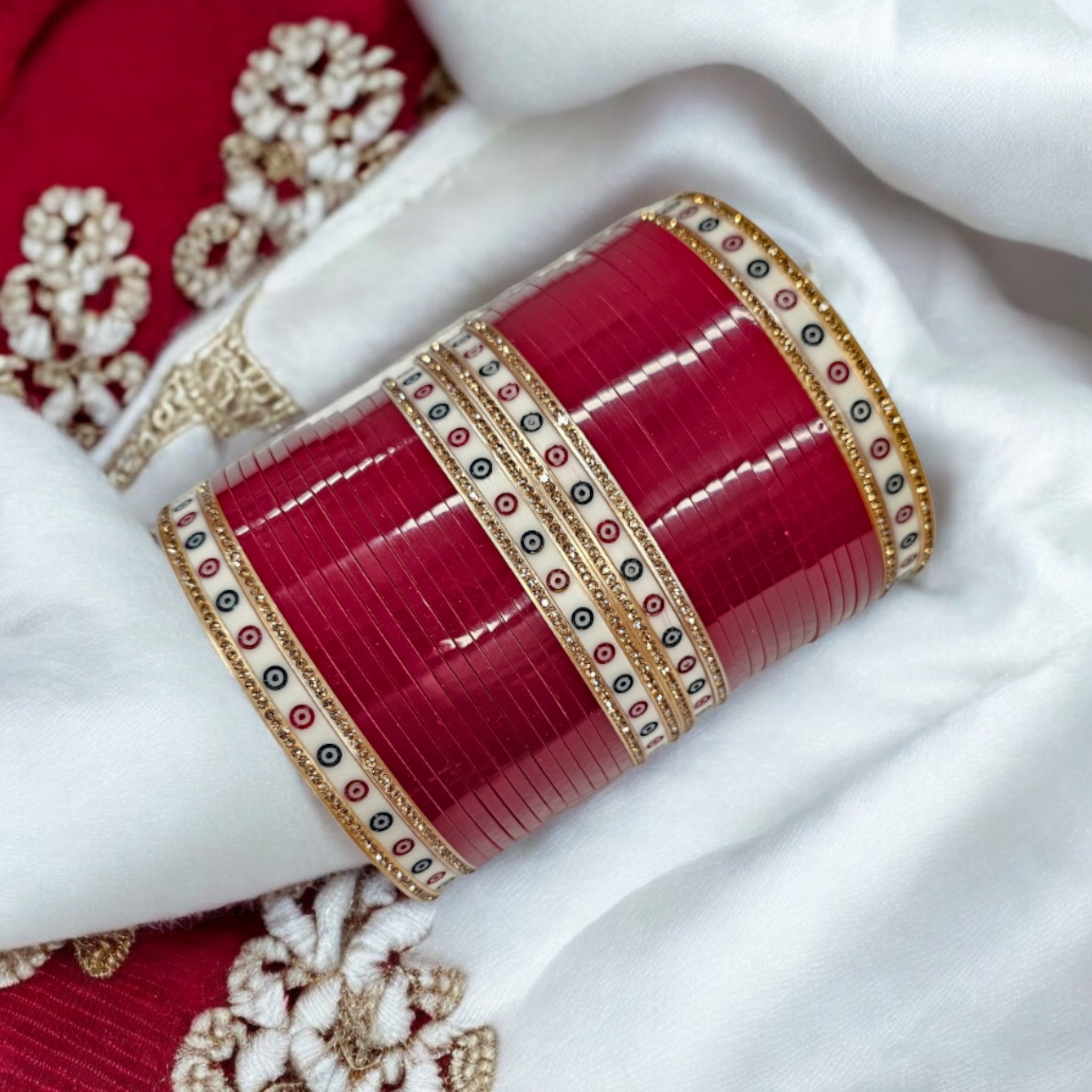 Blood Red Chuda on a red and white and background with rose-gold gemstones.| Wedding Chura Bangle Set