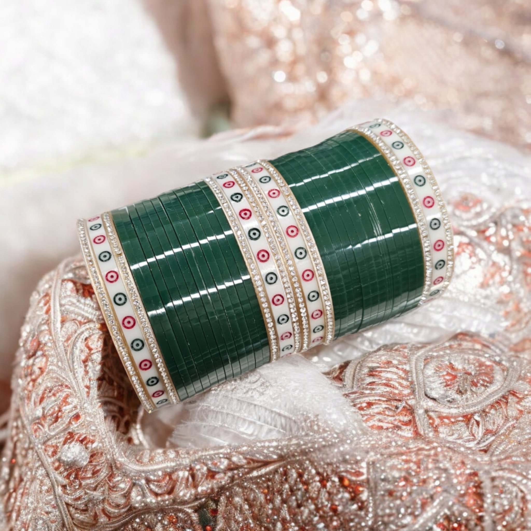 Green Chura with silver gemstones on a pink embroidered background.