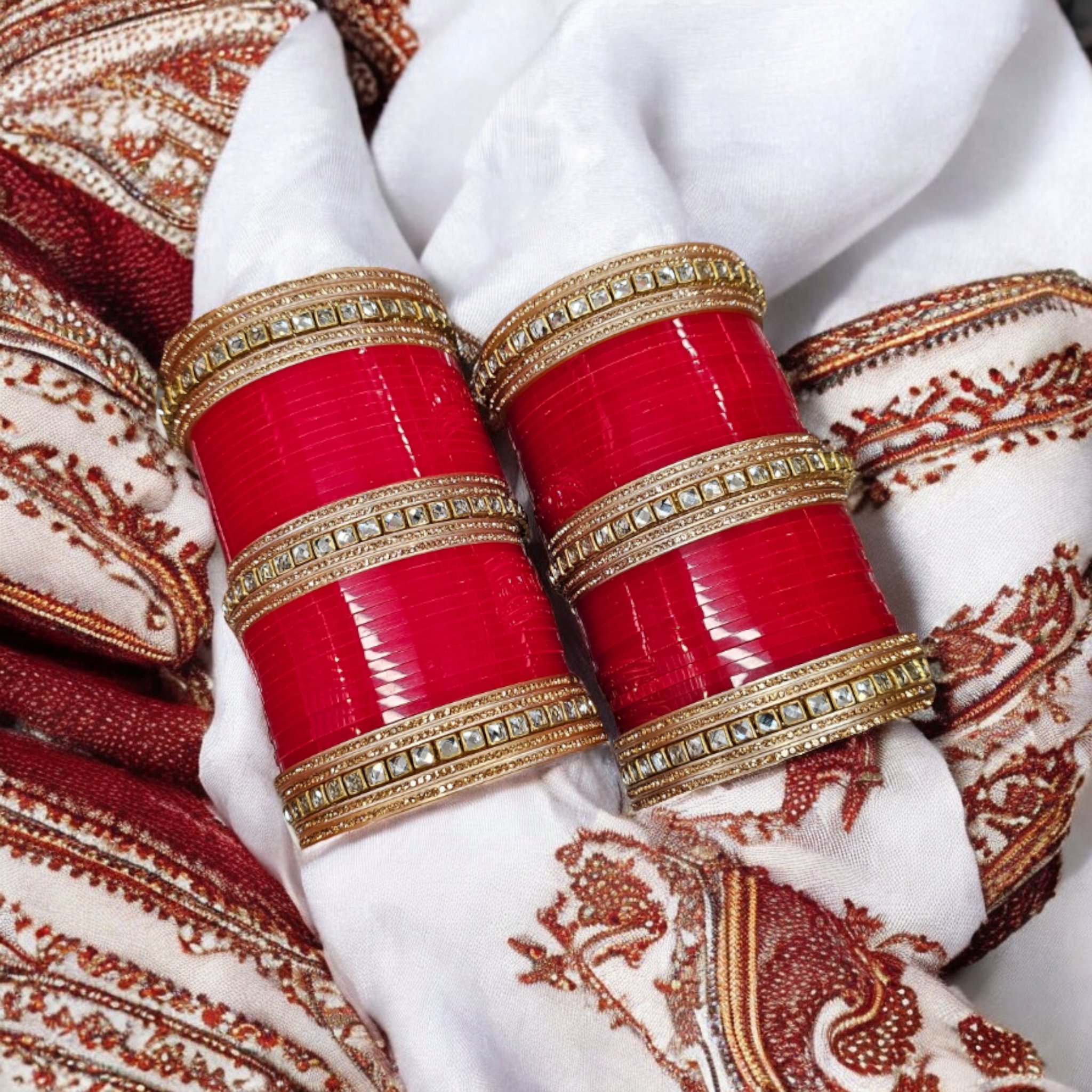 Designer Red Chura with rose-gold gemstones on an embroidered scarf as the background.