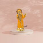 Buy Sai Baba car dashboard idol in Canada and US. Orange Sai Baba idol on a pink background.