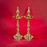 Image of pure Brass Kerala lamps placed on a red background. For sale in Canada and the US