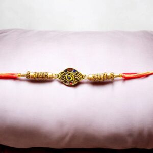 Close-up of Om Rakhi with lustrous red and blue stone detail