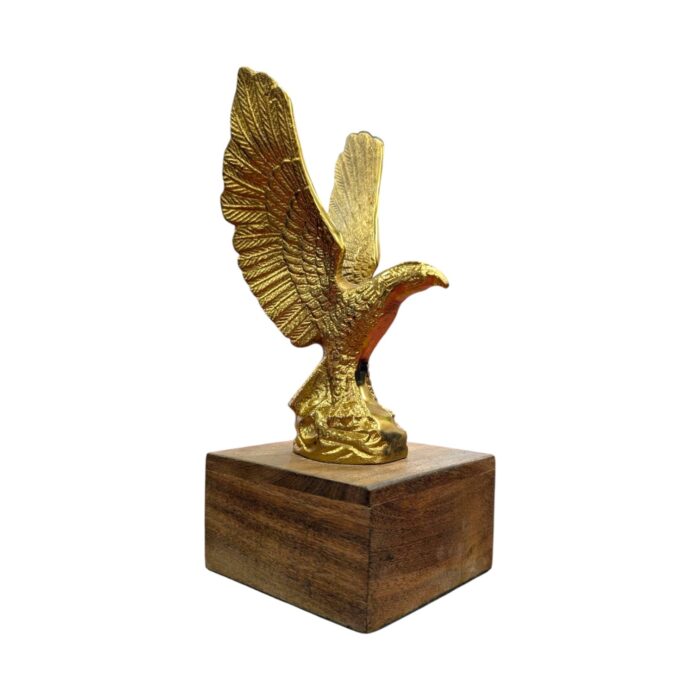 Handcrafted brass flying eagle sculpture on a dark wood base, symbol of freedom and strength.