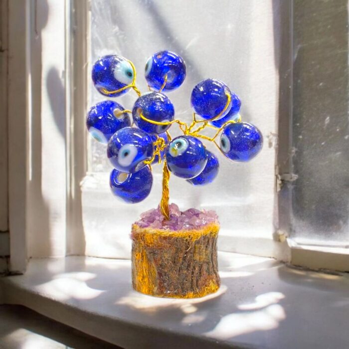 Close-up of a small evil eye protection charm on a brass tree with wooden base.