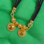 Two Wati Mangalsutra necklace with gold plating and black bead chain, laid flat on a velvet pad.