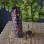 Copper water bottle next to plants, representing a wellness lifestyle.